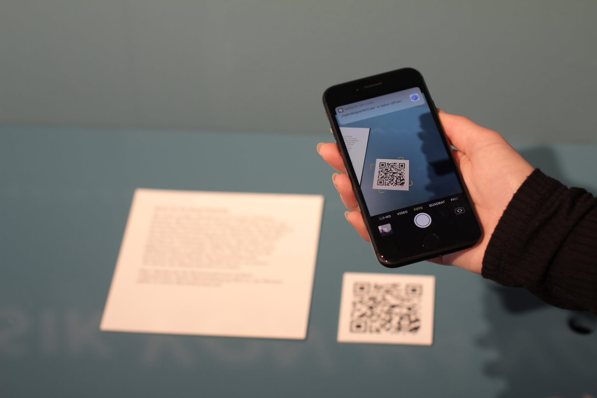 Eine Frau scant mit ihrem Smartphone den QR-Code einer QR-Audiostation